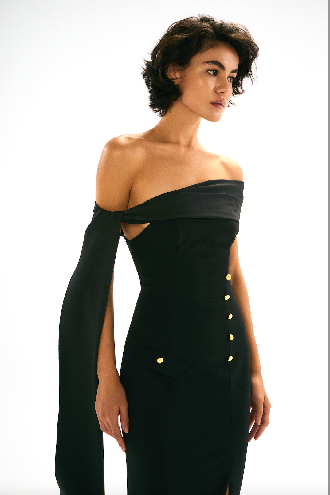 Black off-shoulder dress with gold button detailing. Side