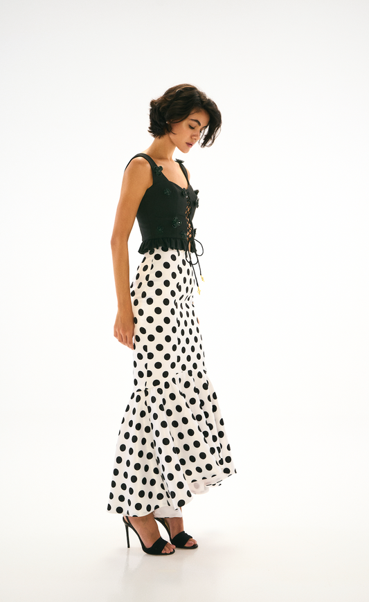 Black cropped Top with rope and flower detailing. High waisted polka dot skirt. Side.
