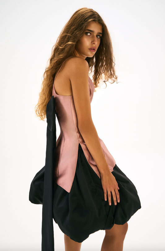 Pink fitted top with black bow detailing at the back. Side. 